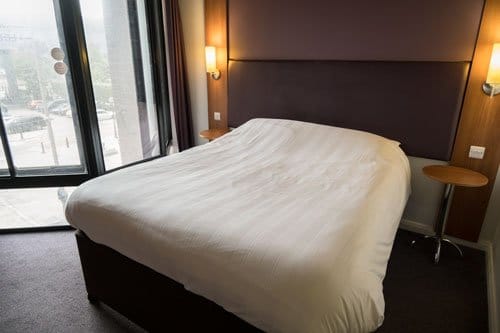 double bed with white linen in hotel room