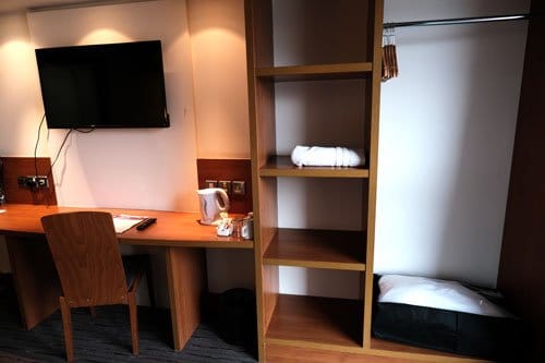 hotel room with shelving unit and desk