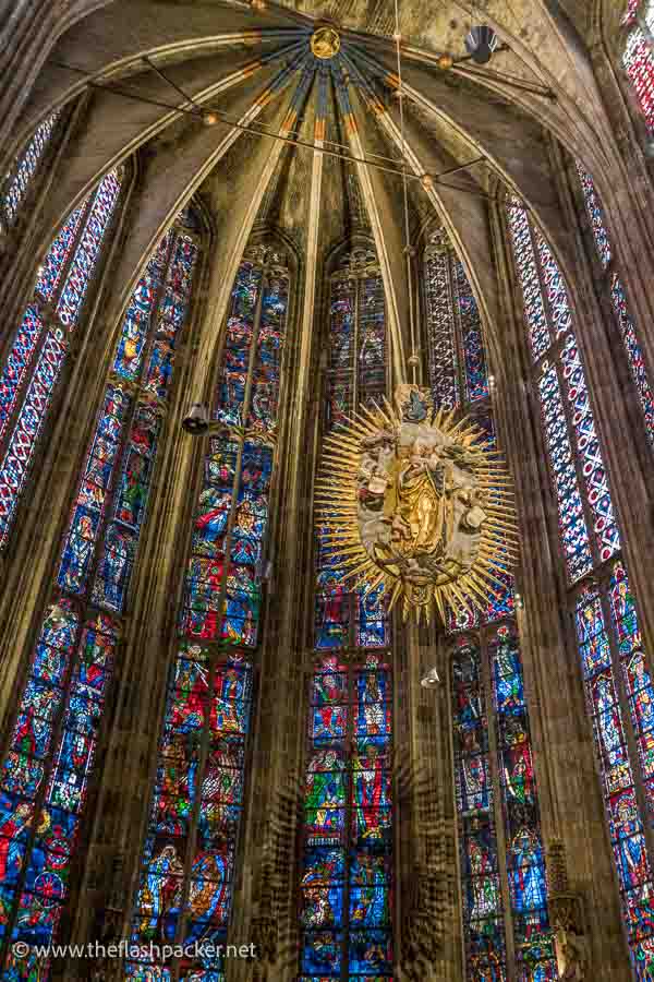 vibrant stained glass windows in a church apse with a central large golden medallion