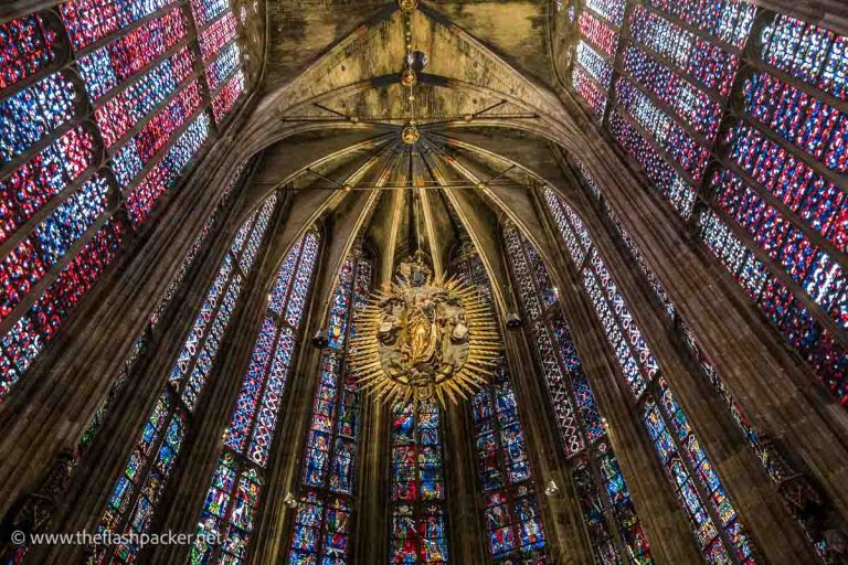 vibrant stained glass windows in a church apse with a central large golden medallion