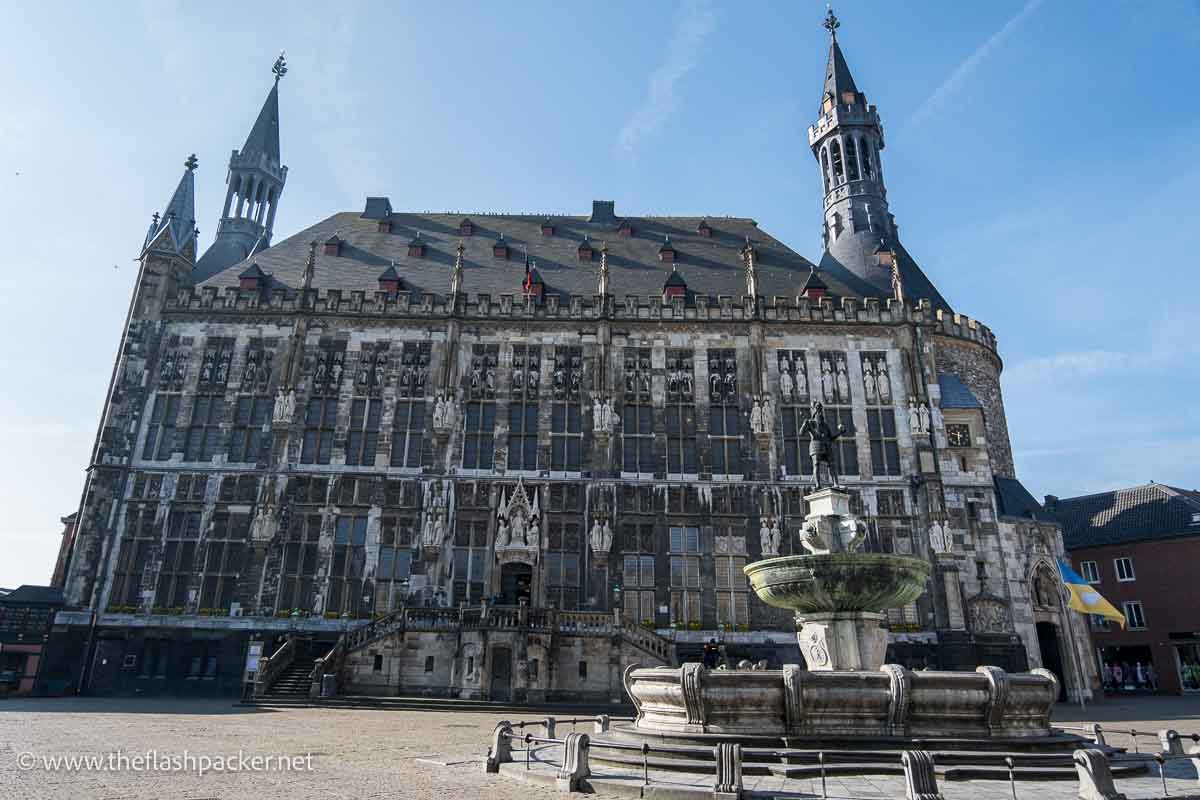 gothic city hall building in aachen behind a fountain