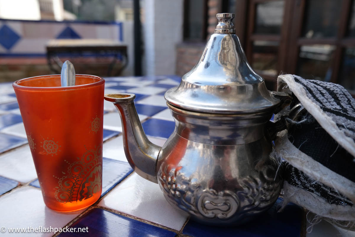 ornate silver tea pot and red glass with spoon