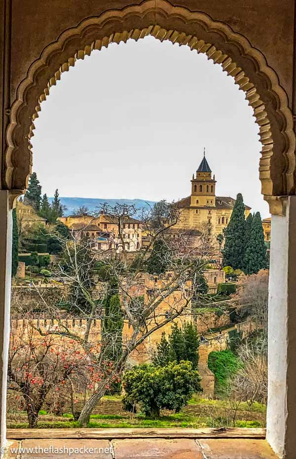 view of old buildings of alhambra through an islamic arch