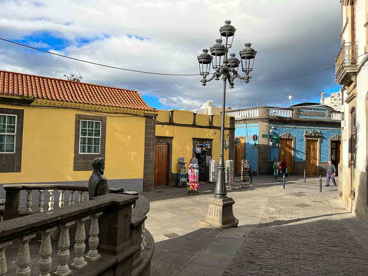 street with single-storey yellow and blue colonial buildings in arucas gran canaria