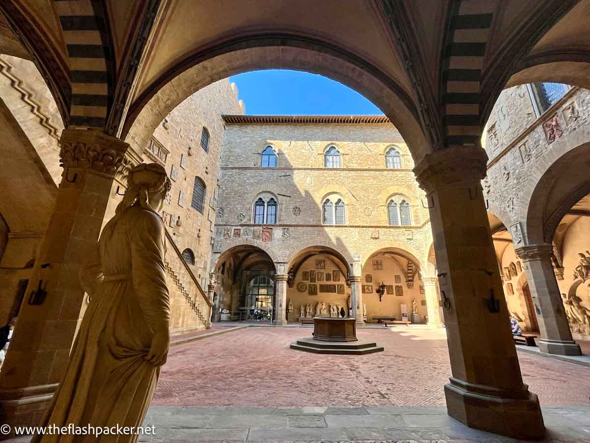 courtyard of renaissance palazzo seen through an arch with statue in foreground