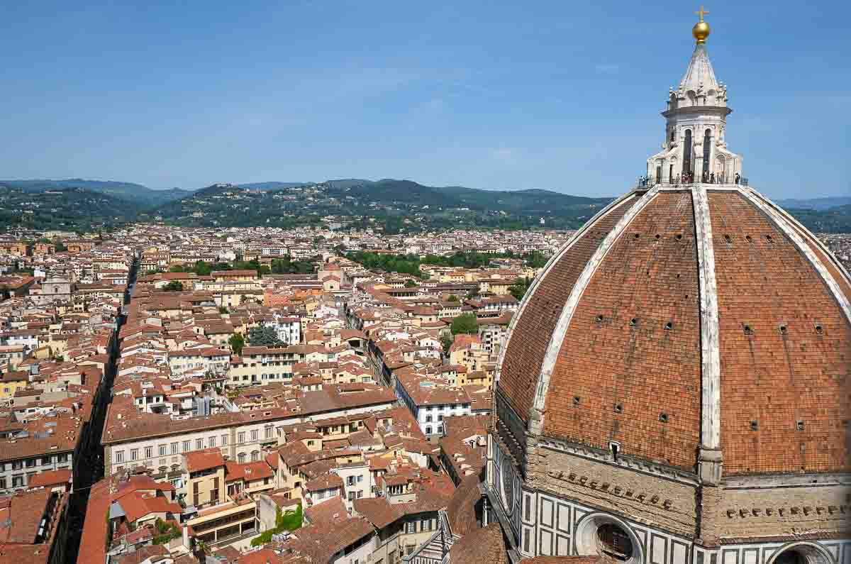 red dome of florence cathedral with red roofs of city below and hills in the distance