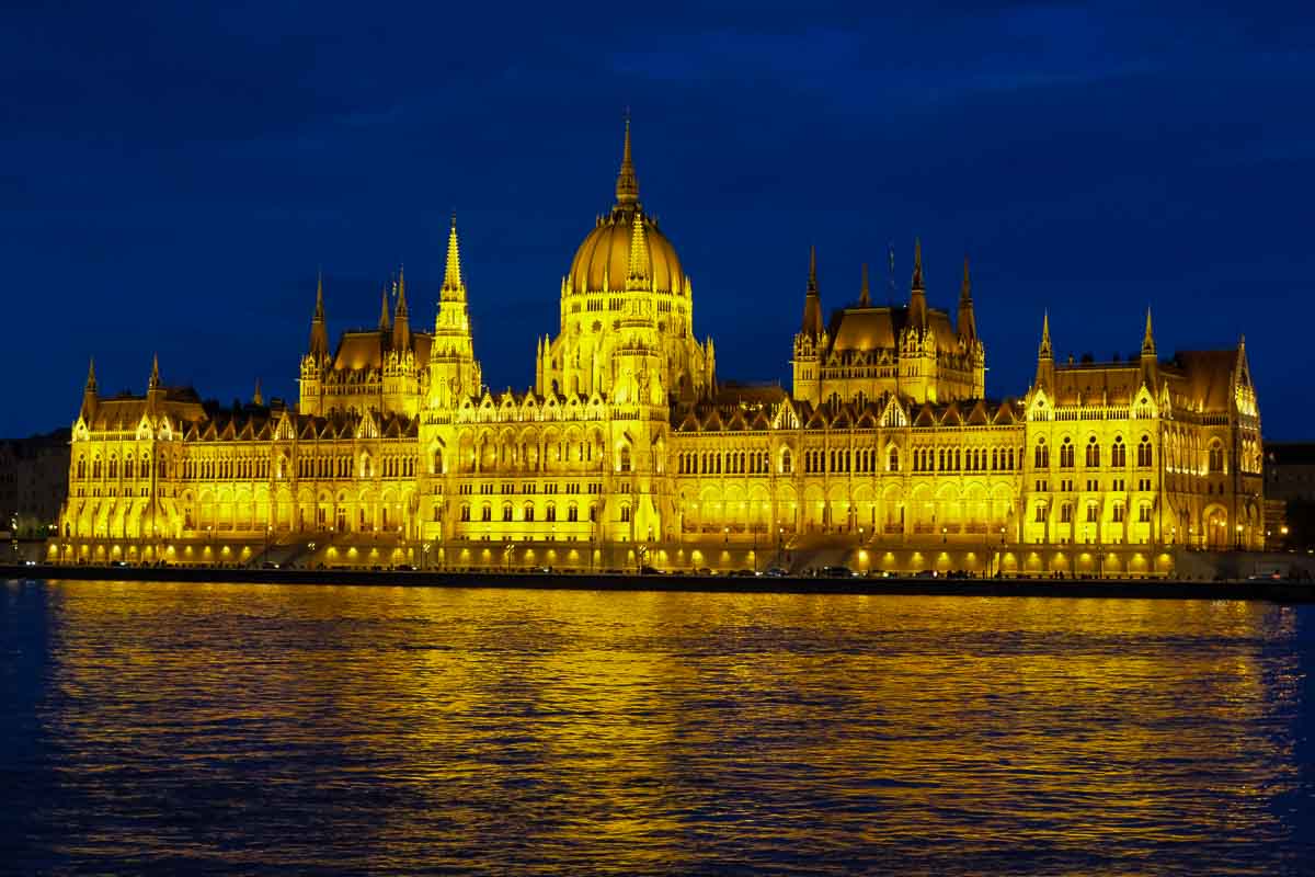 the hungarian parliament building on the banks of the river danube illuminated at night