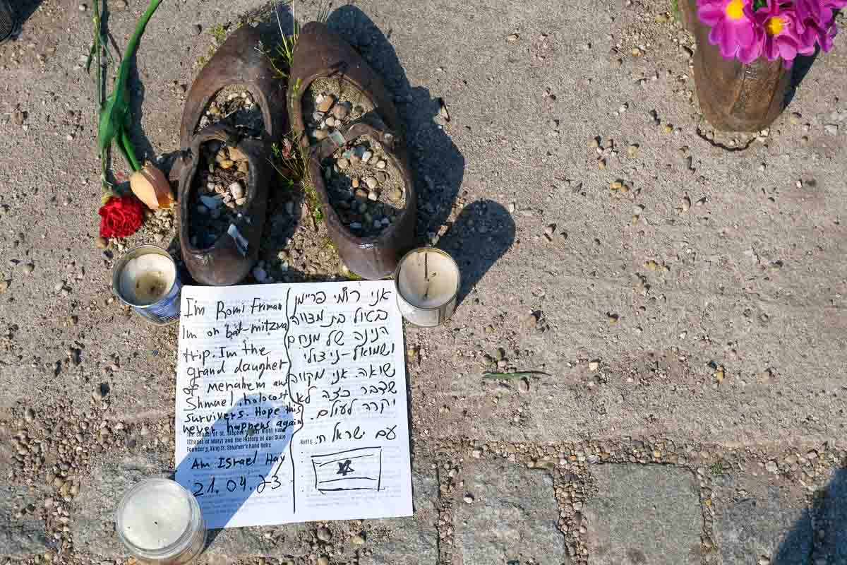 written message, candles and lowers left by sculpture of shoes on the danube in budapest