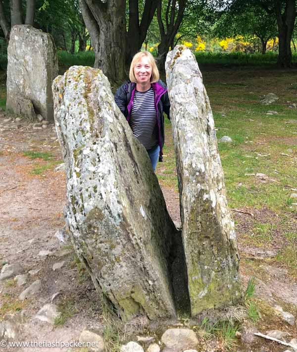 woman peering from between 2 standing stones