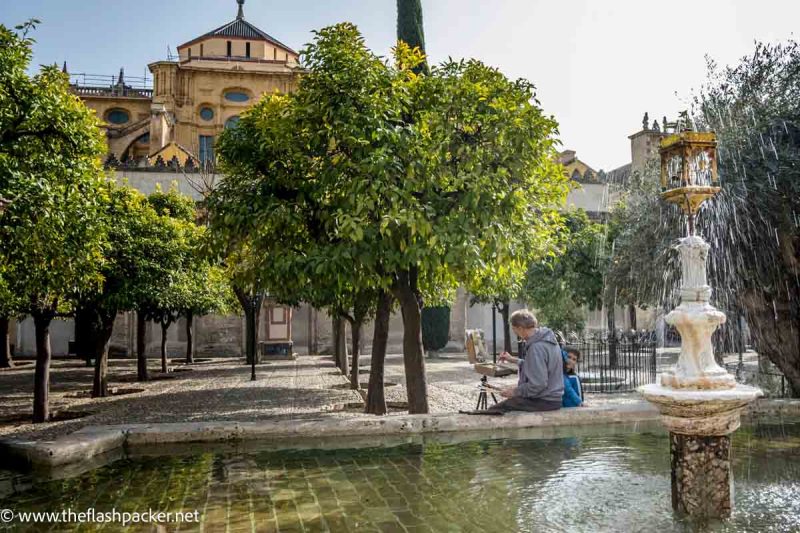 father and son sitting by fountain in courtyard of mezquita of cordoba