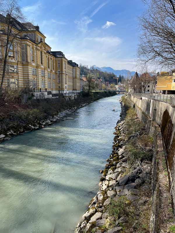 aqua green river lined with old buildings with bridge in distance