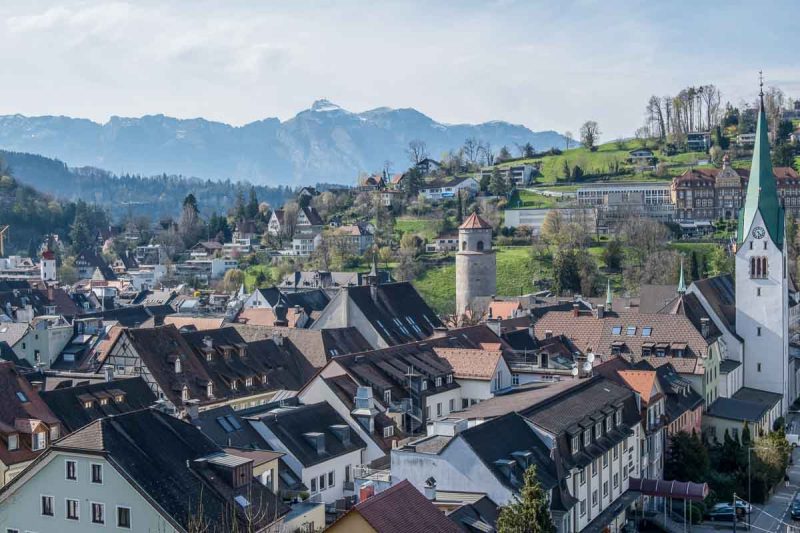 view over the rooftops of feldkirch with cathedral spire and snow covered mountains in distance