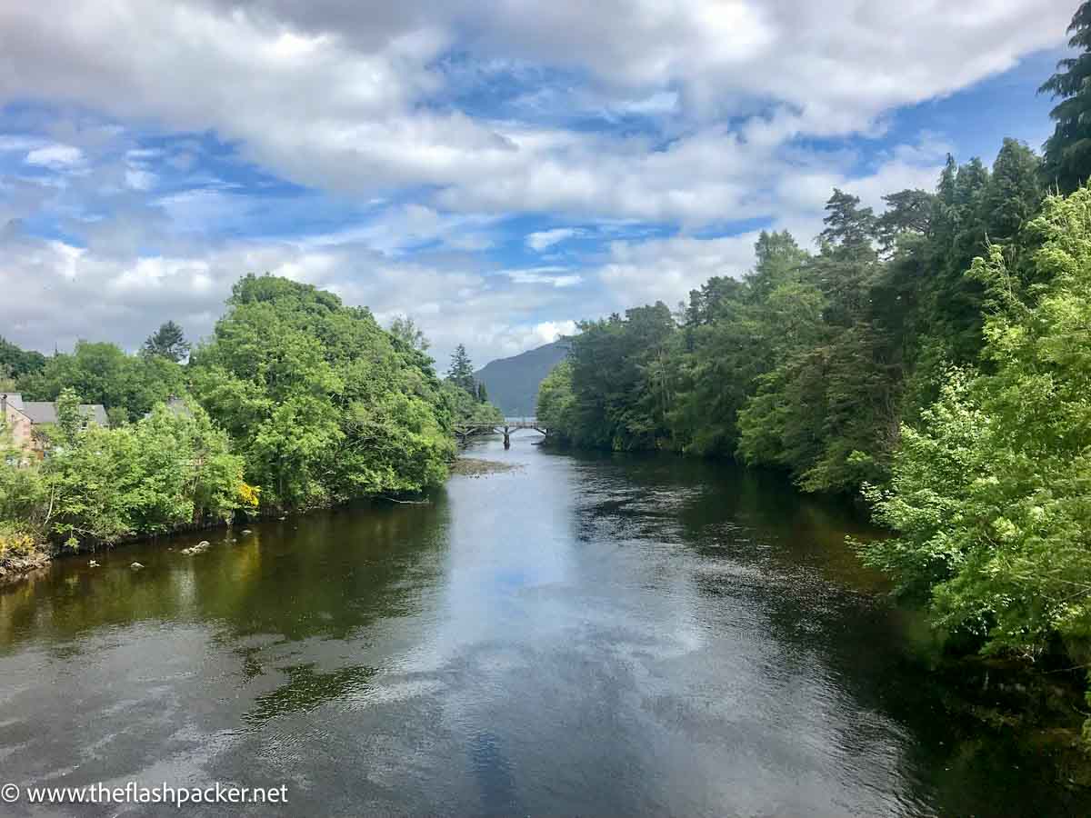 calm river lined with trees on either side at fort augustus scotland