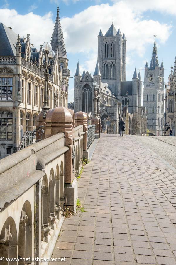 woamn walking across a bridge towards a gothic church