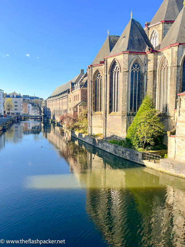 exterior of st michael chruch in ghent with reflection in blue water of canal