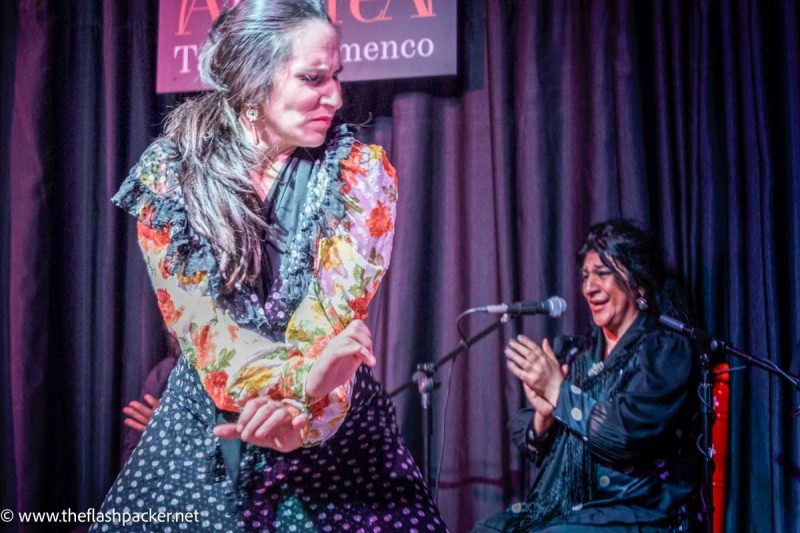 expressive flamenco dancer and singer clapping in background