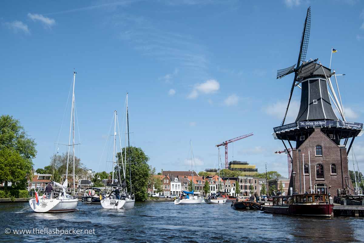 boats on a canal with windmill in haarlem netherlands