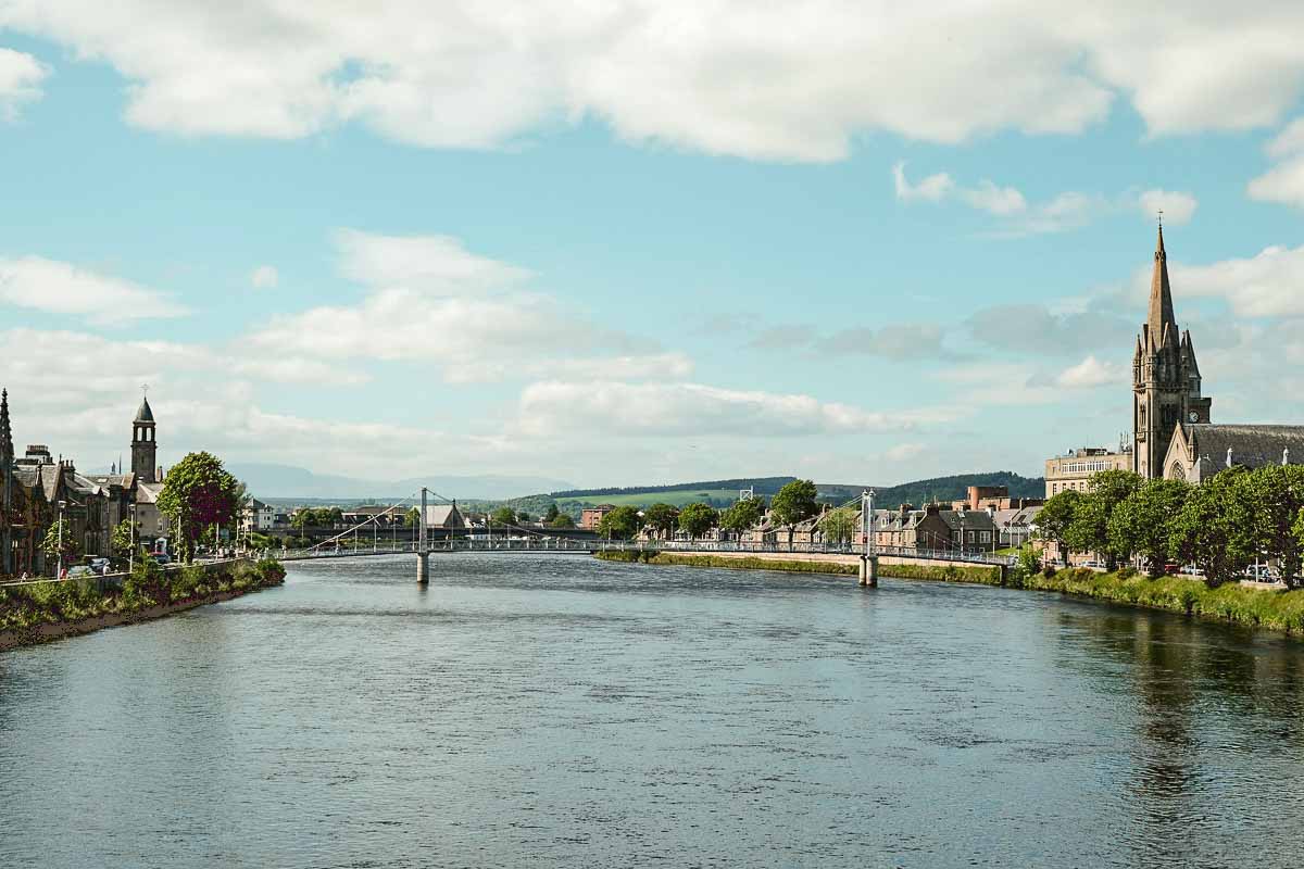 wide river in inverness in scotland with bridge and lined by buuildings