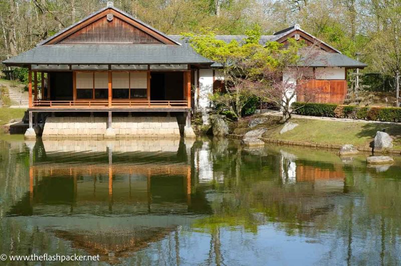 japanese tea house reflected in still water of pond