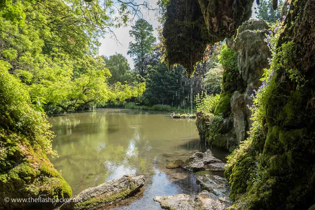 lake with a mossy grotto surrounded by trees