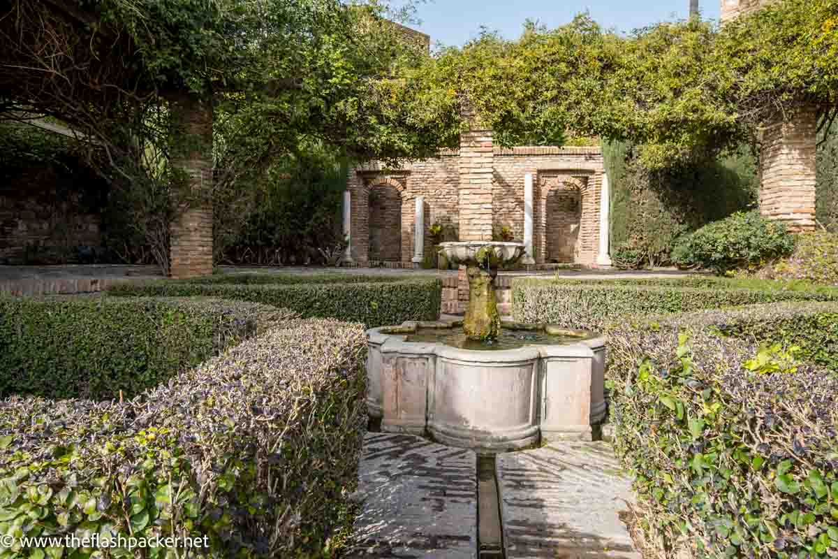 patio garden with low hedges and central fountain in the alcazaba in malaga