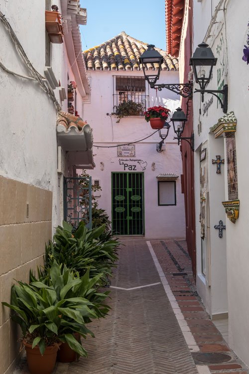 narrow street in marbella old town with pink and white buildings