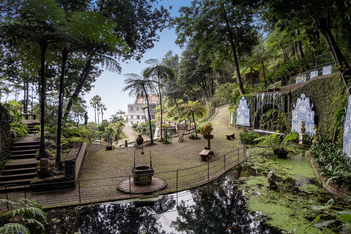 a terraced garden with a lake and waterfall looking down on monte palace madeira