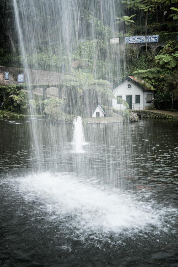 two small houses in lake seen through a wall of water