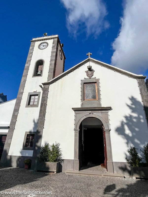 bell tower of church with red roof set against the steep forested slope of valley