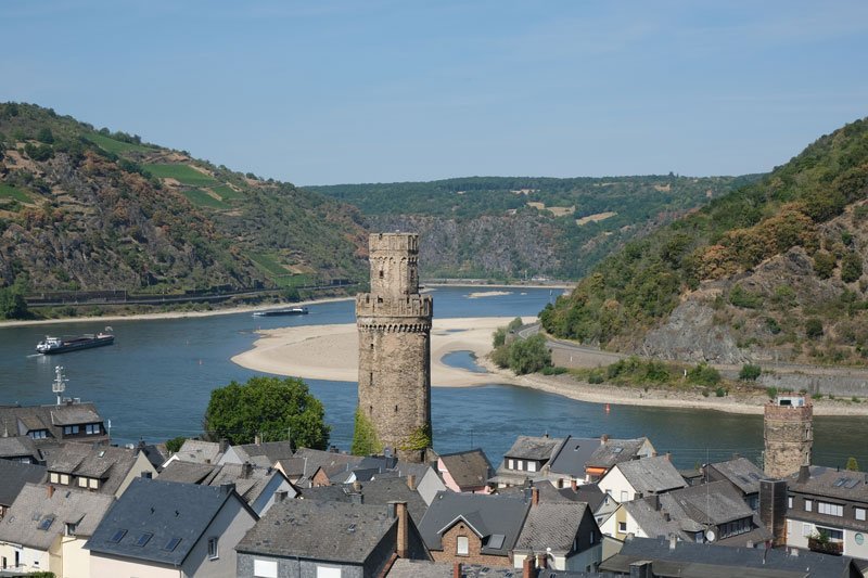 tall tower amongst the rooftops of a town alongside a bend in the river rhine germany