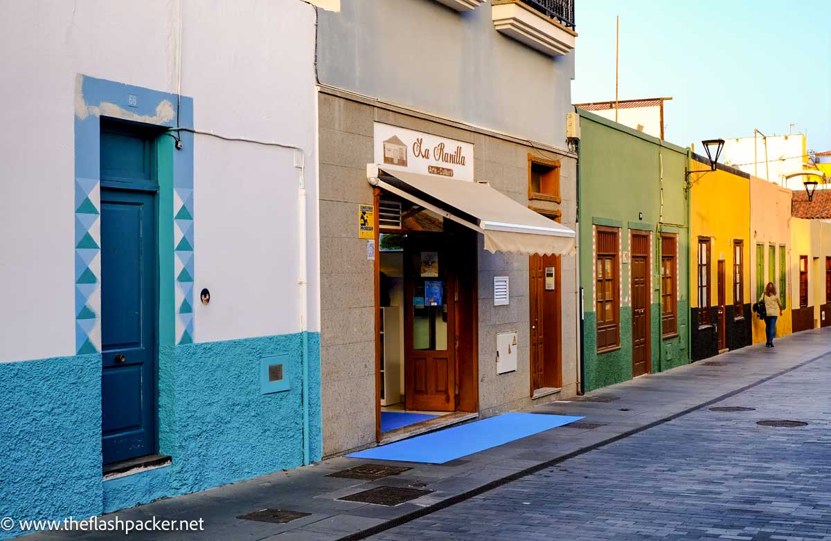 street with multicoloured buildings and woman walking past in puerto de la cruz tenerife