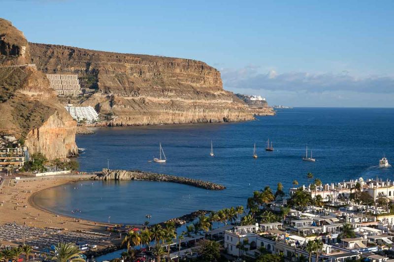 panoramic view of crescent shaped sandy beach backed by cliffs