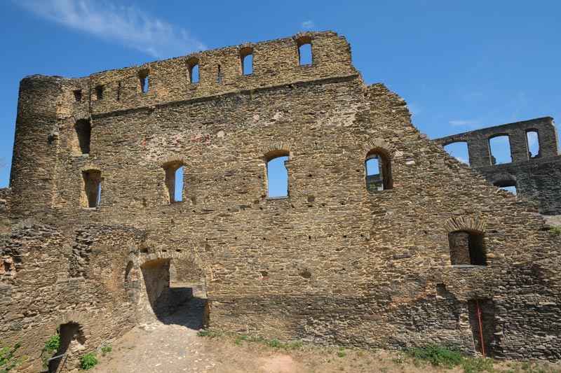 wall of a ruined castle with windwo openings against a blue sky