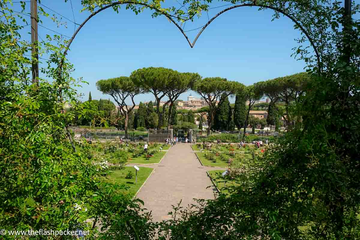 ditant skyline of rome through heart shaped opening in rose garden