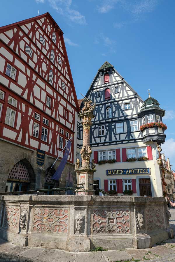 two medieval half timbered buildings and a stone fountain