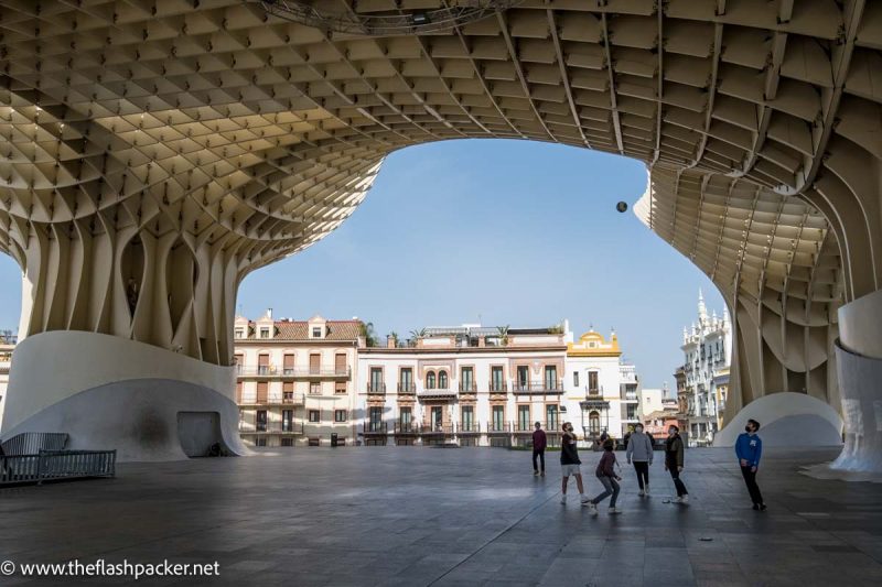 boys playing football under the mushrrom like structure of las seta in seville