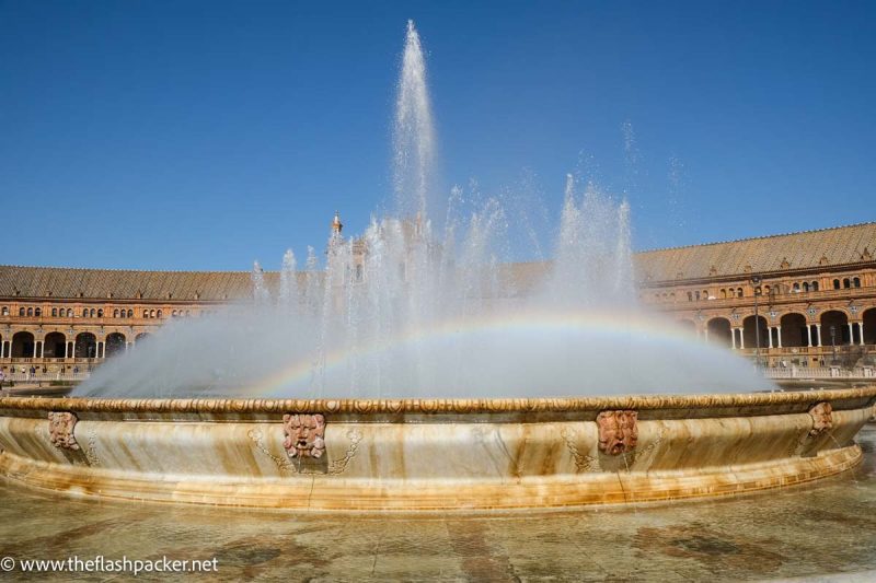 rainbow in fountain in immense colonnaded plaza