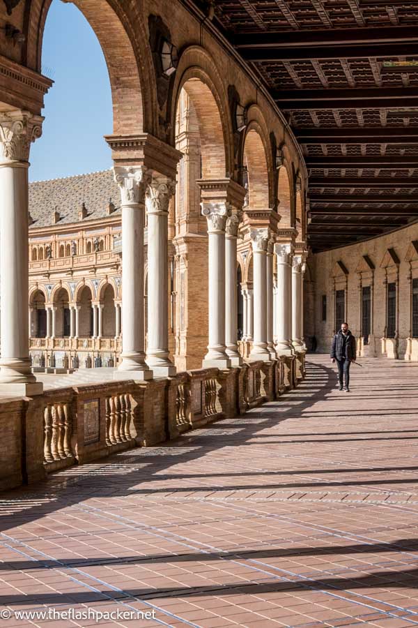 man walking along grand colonnaded walkway