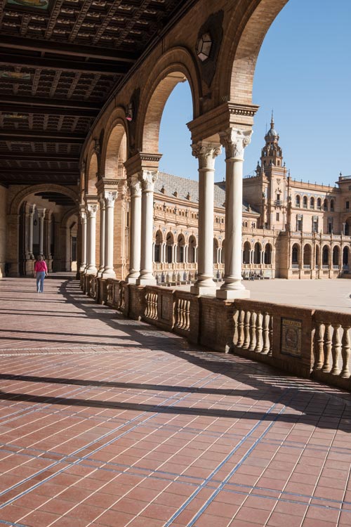 person walking along curved colonnaded walkway