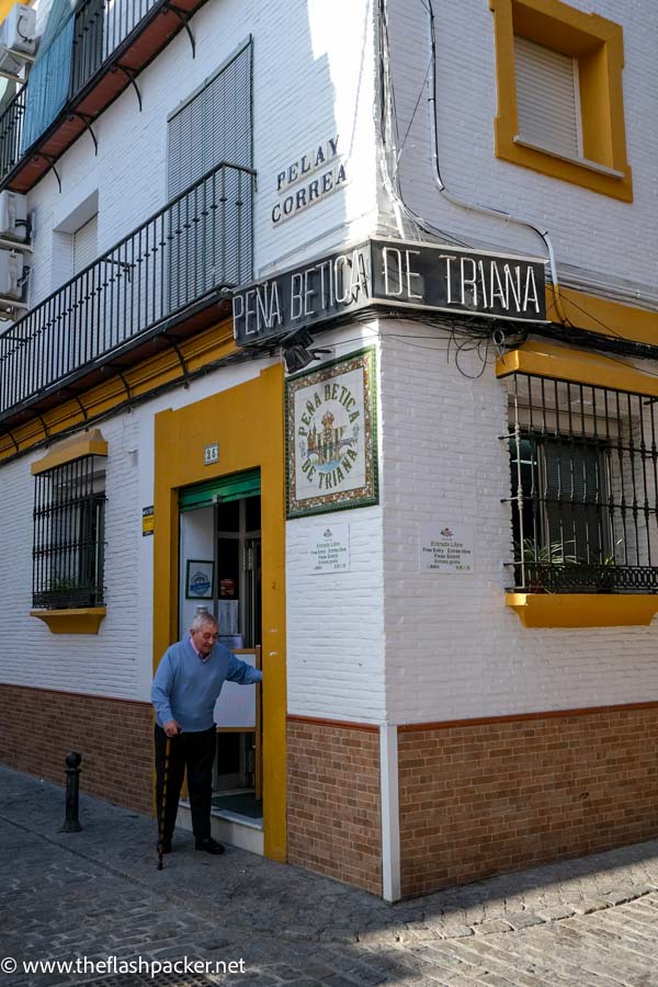 old man stepping out of a cafe on the corner of a street in seville spain