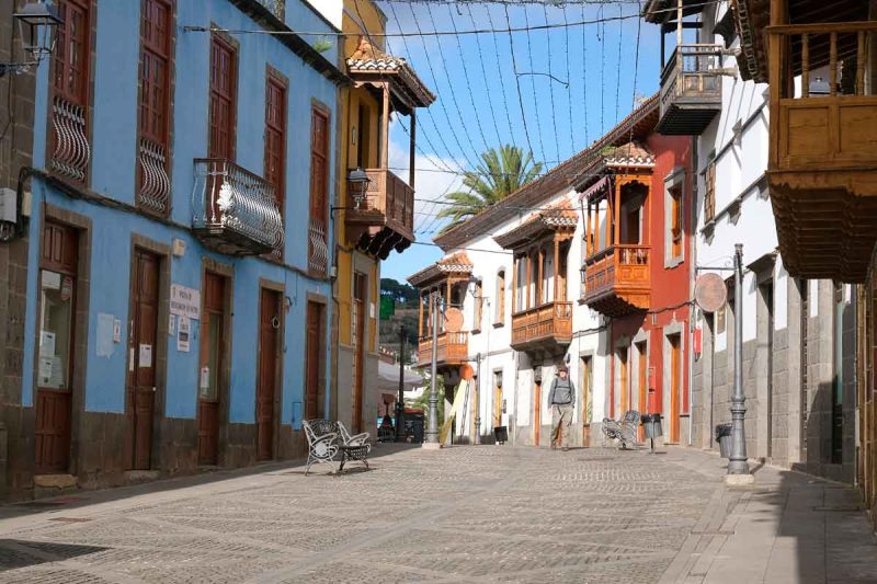 man walking along a street lined with traditional Canarian buildings with wooden balconies