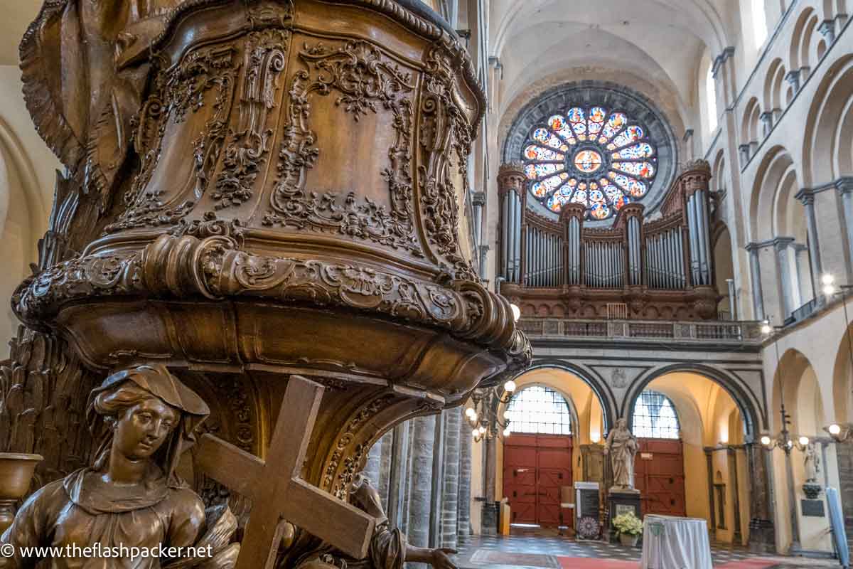 carved wooden pulpit in cathedral with woman holding a cross