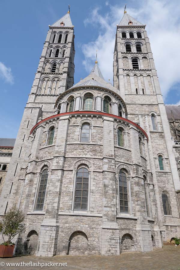 grey stone exterior of tournai cathedral rounded transept and 2 tall towers