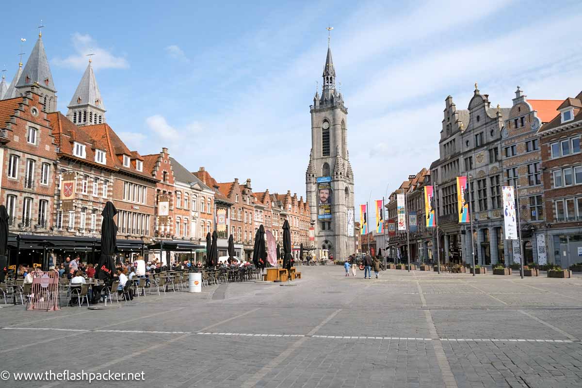 large town square lined with red brick medieval buildings and with a large belfry