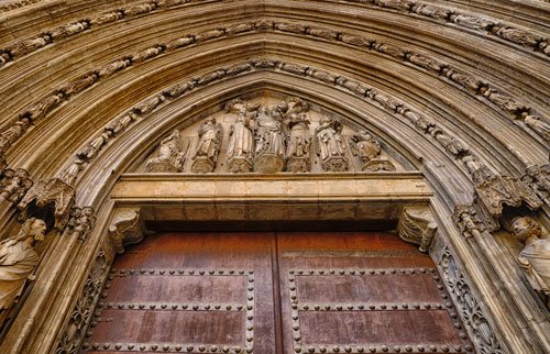 wooden door of cathedral surrounded by finely sculpted figurines