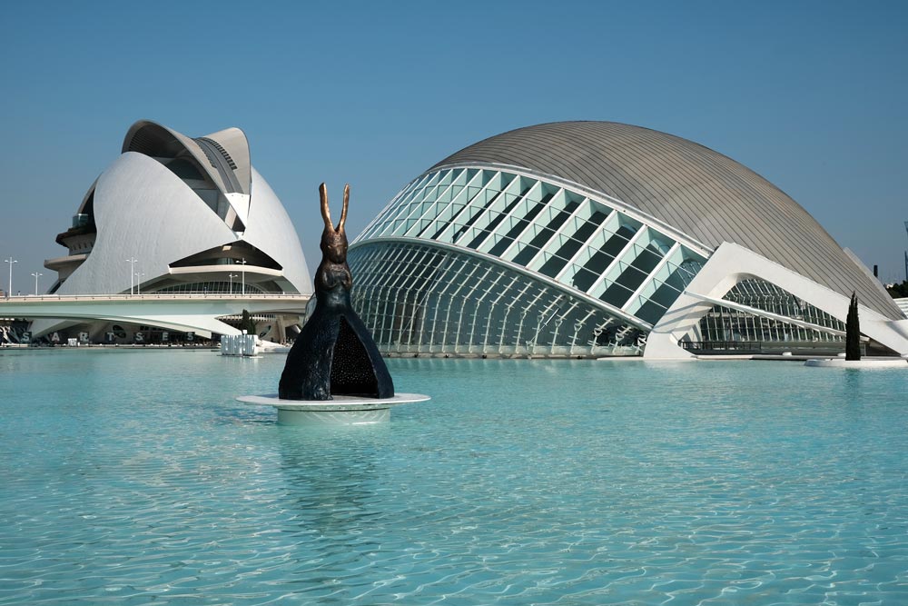 futuristic buildings behind giant pond with sculpture in valencia spain