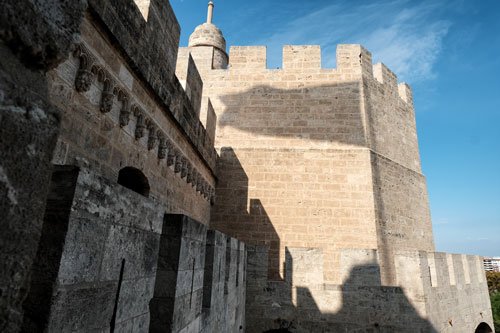 turreted medieval gate with wall with stone sculptings