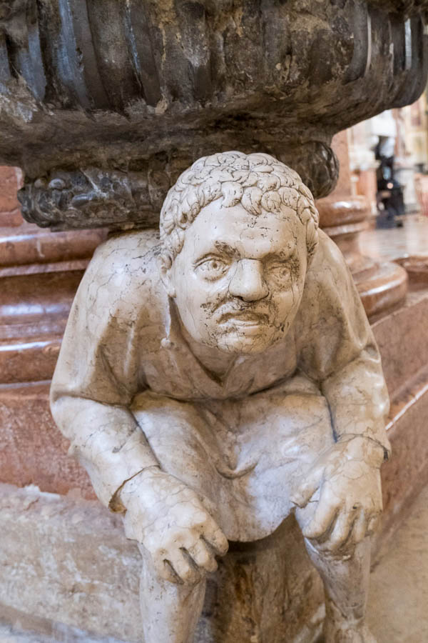 stone sculpture of hunchback holding up a water font