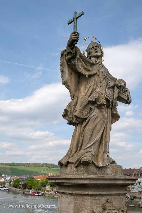 stone statue of a saint holding a crucifix