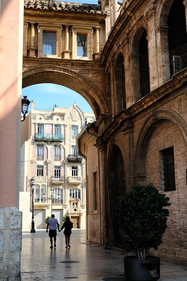 man and woman walking through arch into medieval piazza